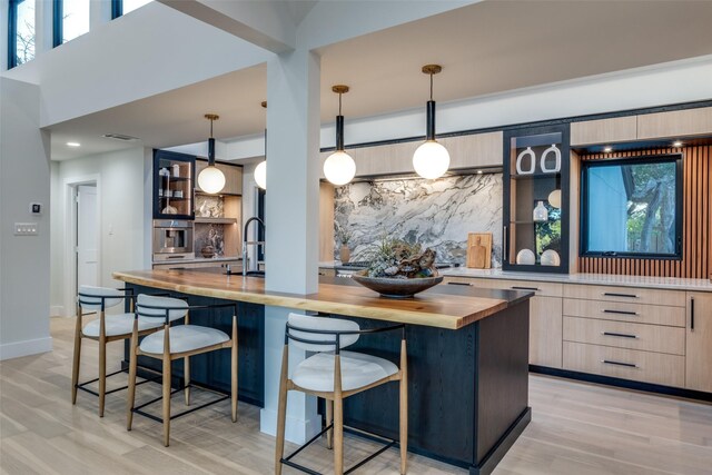 kitchen with a breakfast bar area, light hardwood / wood-style floors, pendant lighting, and wood counters