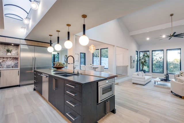 kitchen featuring a healthy amount of sunlight, a kitchen island with sink, sink, and hanging light fixtures