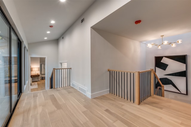 corridor with a chandelier and light hardwood / wood-style floors