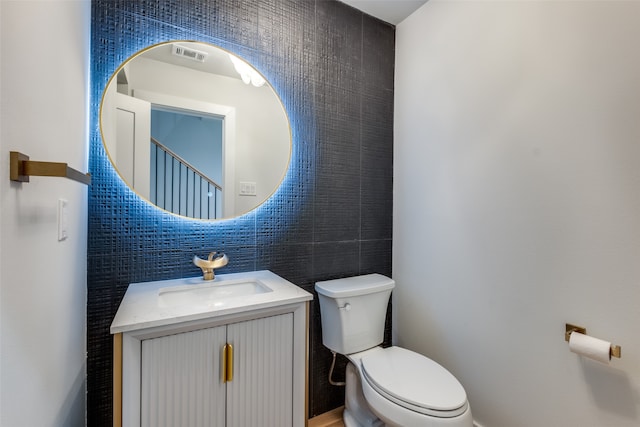 bathroom with vanity, tile walls, and toilet