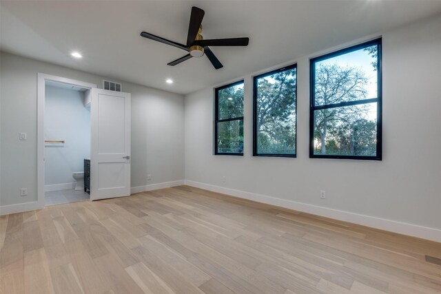 unfurnished bedroom with light wood-type flooring, ceiling fan, and connected bathroom