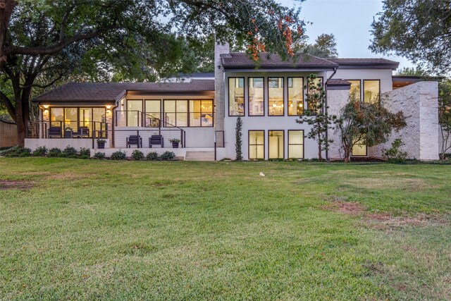 rear view of property with a lawn and a sunroom