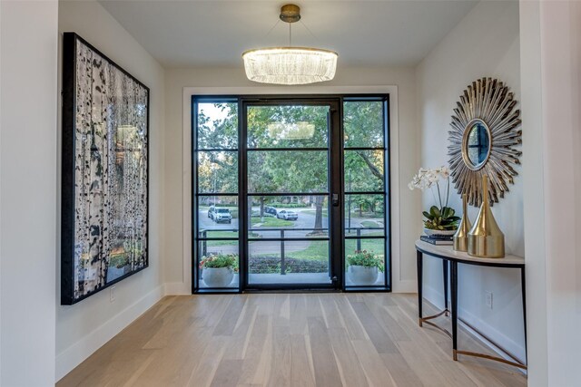 doorway to outside with wood-type flooring and a chandelier