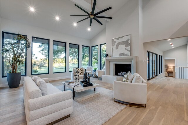 living room with ceiling fan, high vaulted ceiling, and light hardwood / wood-style flooring