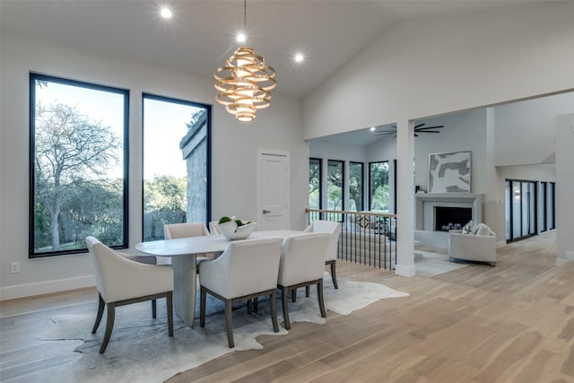 dining space featuring ceiling fan with notable chandelier, light wood-type flooring, high vaulted ceiling, and a wealth of natural light