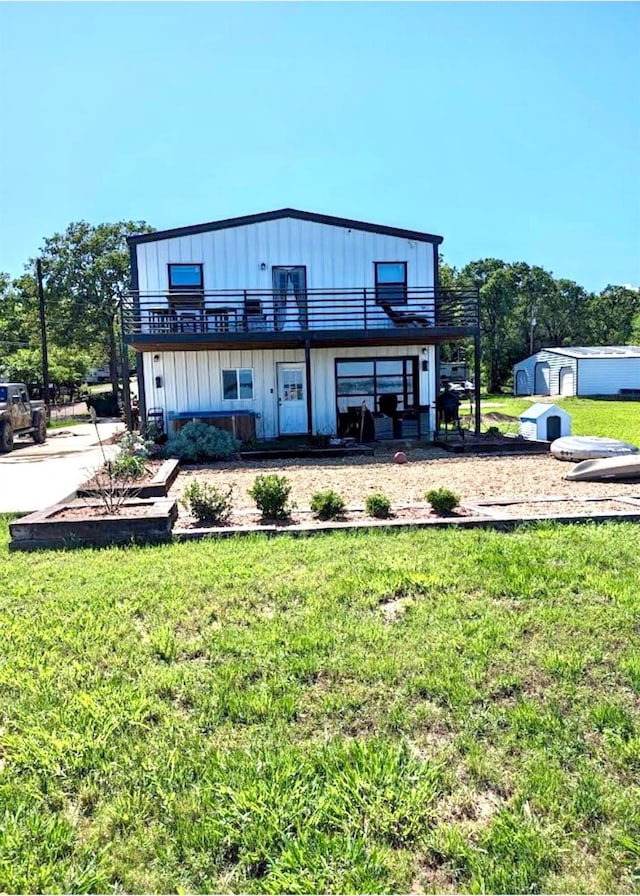 rear view of house with a balcony, a storage unit, and a lawn