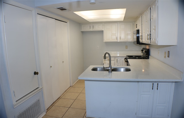 kitchen with kitchen peninsula, sink, light tile patterned floors, white cabinetry, and stainless steel electric range