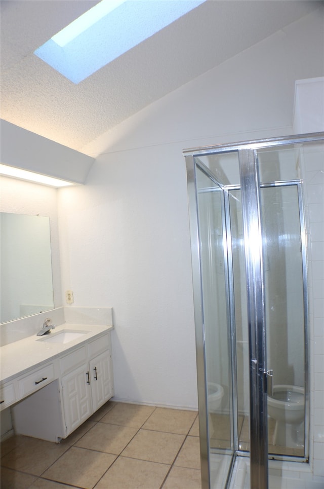 bathroom with tile patterned floors, vaulted ceiling with skylight, a textured ceiling, vanity, and a shower with shower door