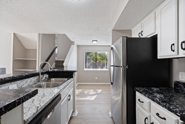 kitchen with sink, light wood-type flooring, a textured ceiling, appliances with stainless steel finishes, and white cabinetry