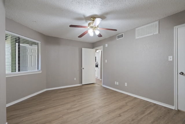 unfurnished room with a textured ceiling, light hardwood / wood-style flooring, and ceiling fan