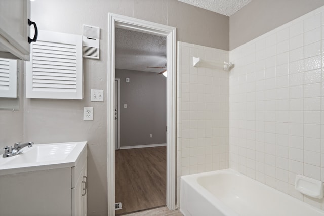 bathroom featuring hardwood / wood-style floors, tiled shower / bath combo, a textured ceiling, and vanity