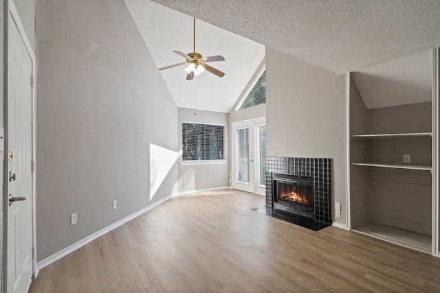 unfurnished living room featuring hardwood / wood-style floors, built in shelves, ceiling fan, and a fireplace