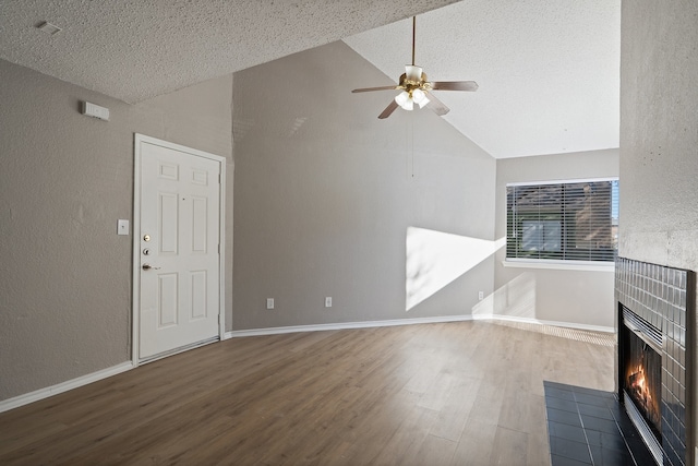 unfurnished living room with a tile fireplace, ceiling fan, high vaulted ceiling, hardwood / wood-style floors, and a textured ceiling