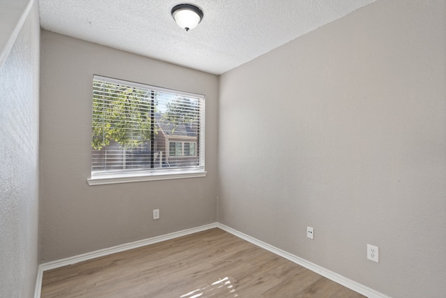 spare room featuring a textured ceiling and light hardwood / wood-style flooring