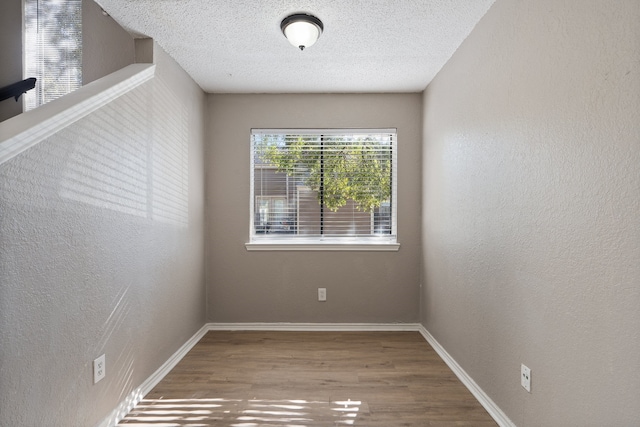 unfurnished room with a textured ceiling and hardwood / wood-style flooring