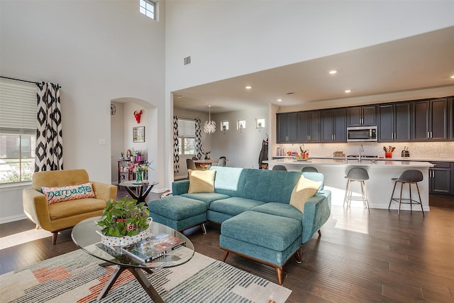 living room with dark hardwood / wood-style flooring, sink, and a high ceiling