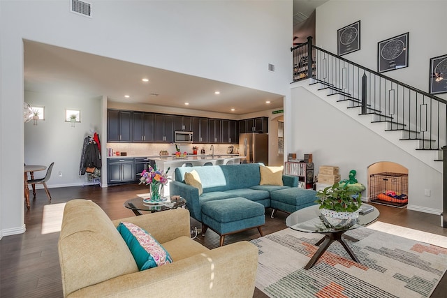 living room with a high ceiling and dark wood-type flooring