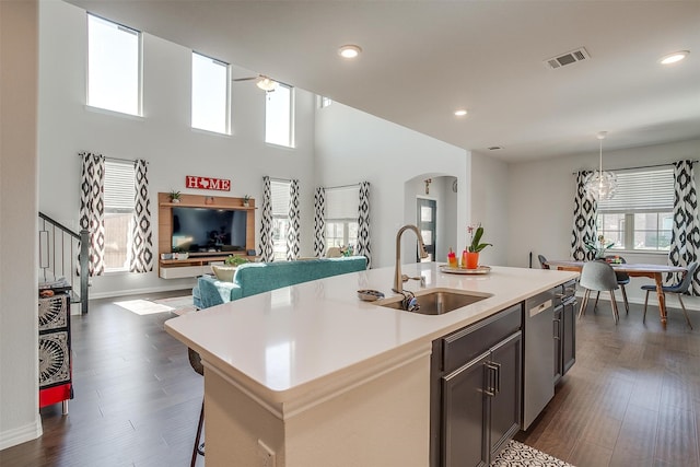 kitchen featuring dark wood-type flooring, sink, a healthy amount of sunlight, and a center island with sink