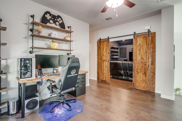 office featuring a barn door, ceiling fan, and hardwood / wood-style flooring