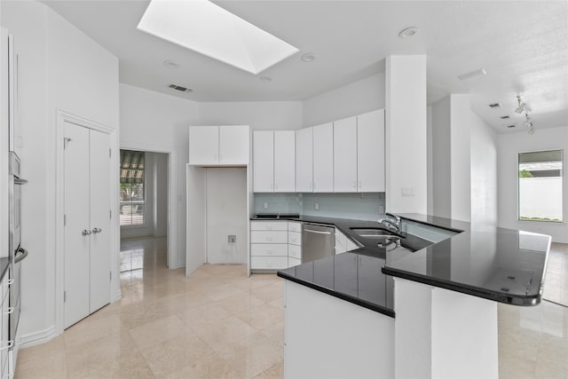 kitchen with kitchen peninsula, white cabinets, dishwasher, and sink