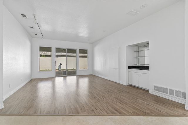 unfurnished living room with rail lighting and light wood-type flooring