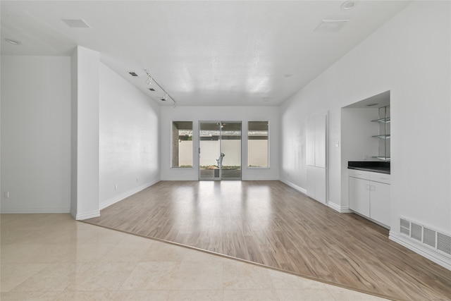 unfurnished living room with track lighting and light hardwood / wood-style flooring