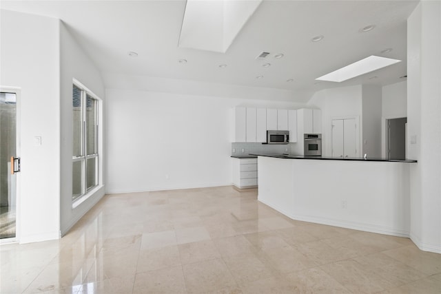 kitchen with appliances with stainless steel finishes, a skylight, and white cabinetry