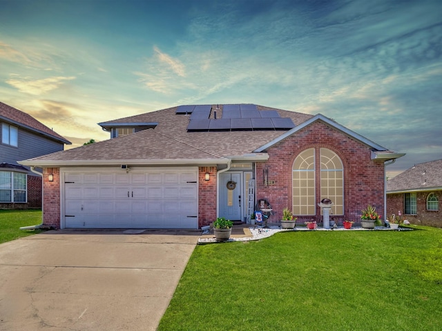 view of front facade with a lawn, a garage, and solar panels