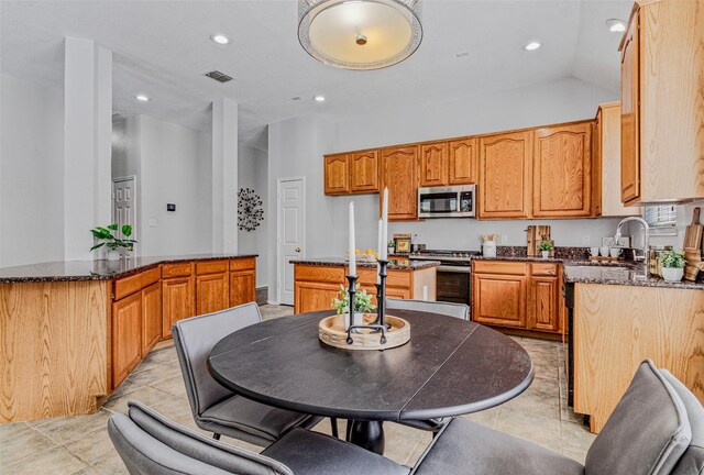 kitchen featuring light tile patterned flooring, sink, vaulted ceiling, appliances with stainless steel finishes, and a kitchen island