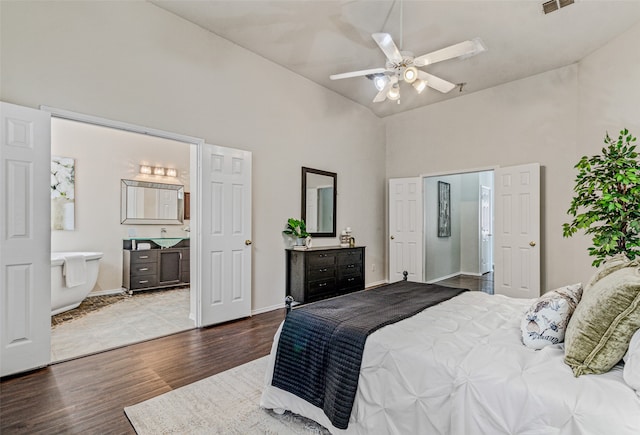 bedroom with hardwood / wood-style floors, high vaulted ceiling, ensuite bath, and ceiling fan