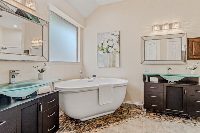 bathroom with a bathtub, vanity, and lofted ceiling