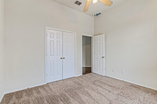 unfurnished bedroom featuring carpet flooring, ceiling fan, high vaulted ceiling, and a closet