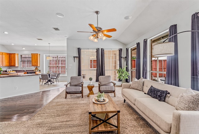 living room with ceiling fan, light hardwood / wood-style flooring, vaulted ceiling, and sink