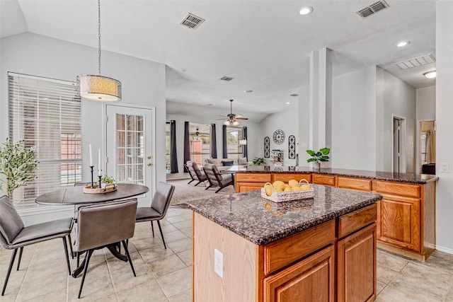 kitchen featuring pendant lighting, light tile patterned floors, a wealth of natural light, and dark stone countertops