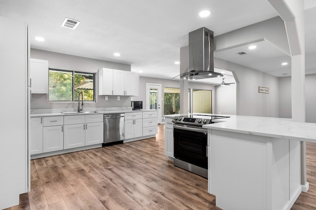 kitchen featuring island range hood, white cabinetry, sink, and appliances with stainless steel finishes