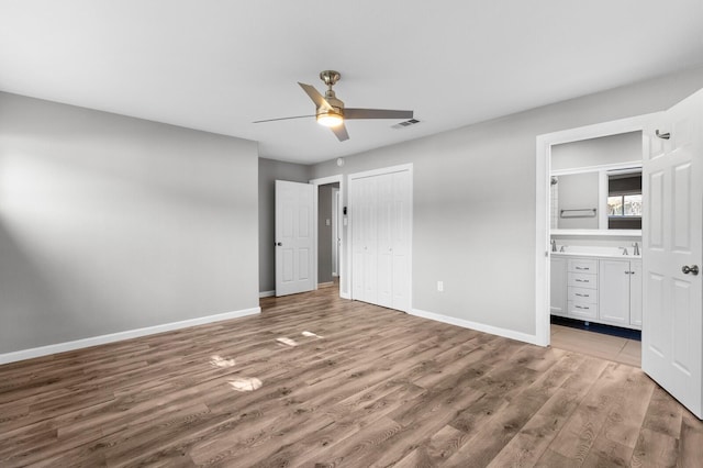 unfurnished bedroom with hardwood / wood-style floors, ceiling fan, sink, and ensuite bath