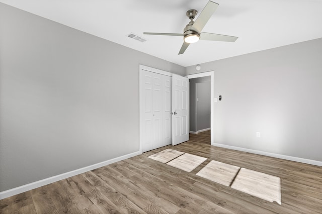 unfurnished bedroom featuring hardwood / wood-style flooring, ceiling fan, and a closet