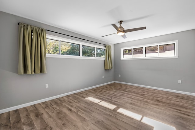 spare room featuring hardwood / wood-style floors, ceiling fan, and a wealth of natural light