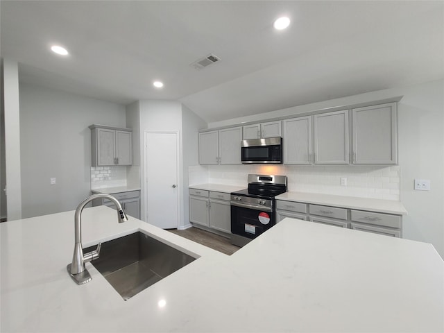 kitchen featuring appliances with stainless steel finishes, sink, decorative backsplash, and gray cabinetry