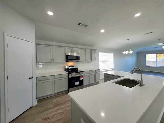 kitchen with gray cabinetry, plenty of natural light, an island with sink, and appliances with stainless steel finishes