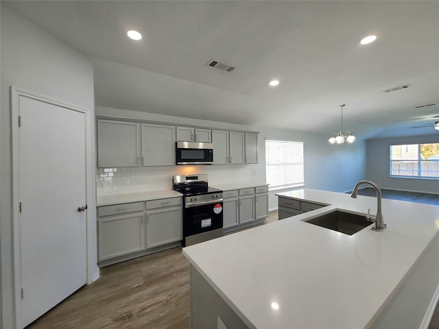 kitchen with gray cabinets, pendant lighting, sink, a kitchen island with sink, and stainless steel appliances