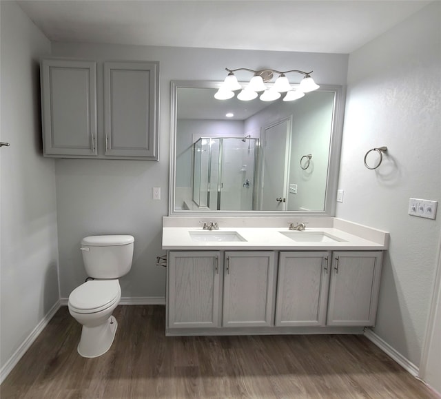 bathroom with toilet, vanity, a shower with shower door, and hardwood / wood-style flooring