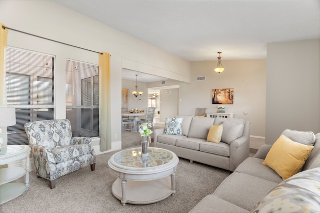 carpeted living room featuring a notable chandelier