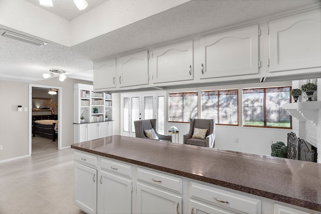 kitchen with a fireplace, white cabinetry, and a textured ceiling