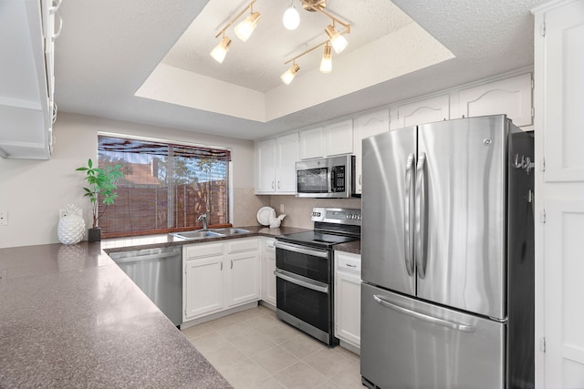 kitchen featuring white cabinets, a textured ceiling, appliances with stainless steel finishes, and a tray ceiling