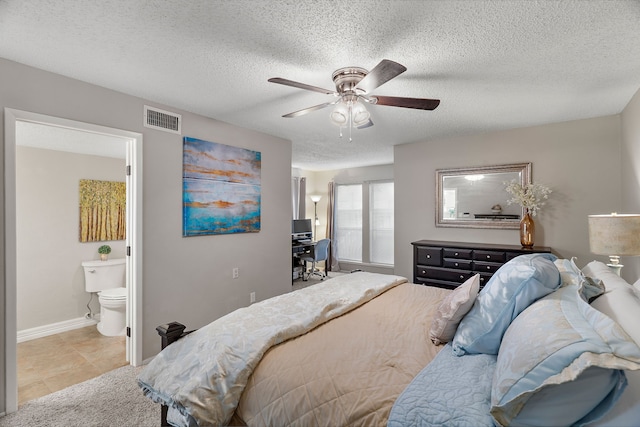 tiled bedroom with ensuite bath, ceiling fan, and a textured ceiling