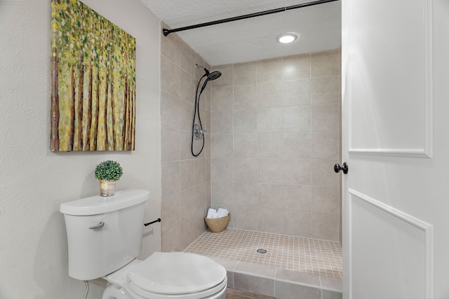 bathroom with a tile shower, a textured ceiling, and toilet