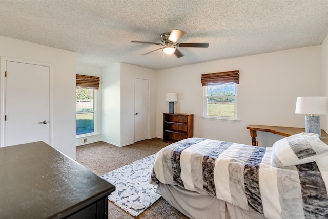 carpeted bedroom featuring ceiling fan, a textured ceiling, and multiple windows