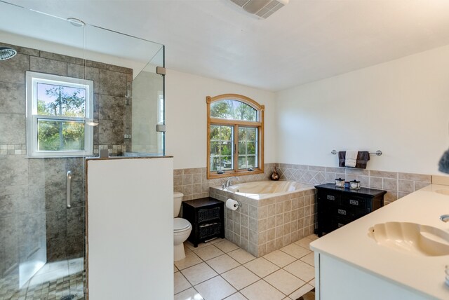 full bathroom with tile patterned floors, vanity, a healthy amount of sunlight, and toilet