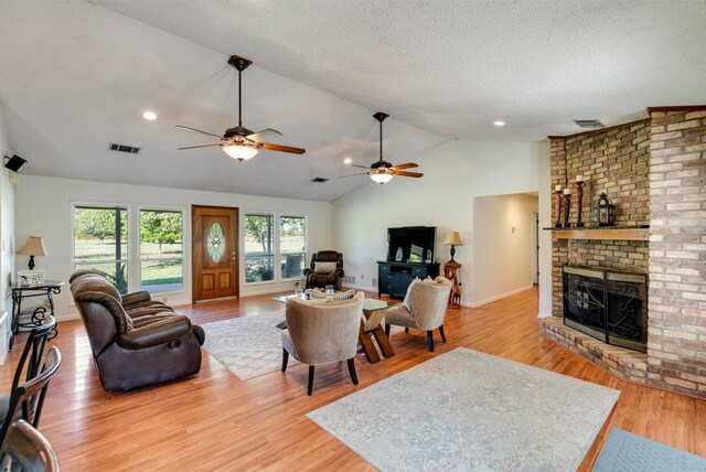 living room with light hardwood / wood-style floors, a brick fireplace, ceiling fan, and lofted ceiling